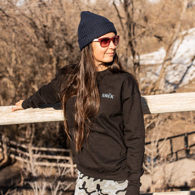 snek cycling logo crewneck sweatshirt on a female model outdoors with knit snek beanie